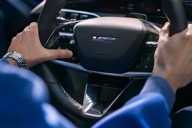 Close-up of a Man About to Press the V-Button on the 2026 OPTIQ-V Steering Wheel | Carl Cannon Chevrolet Buick GMC in Jasper AL