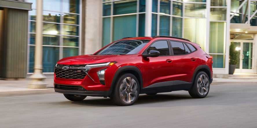 A red 2026 Chevrolet Trax driving through a town.
