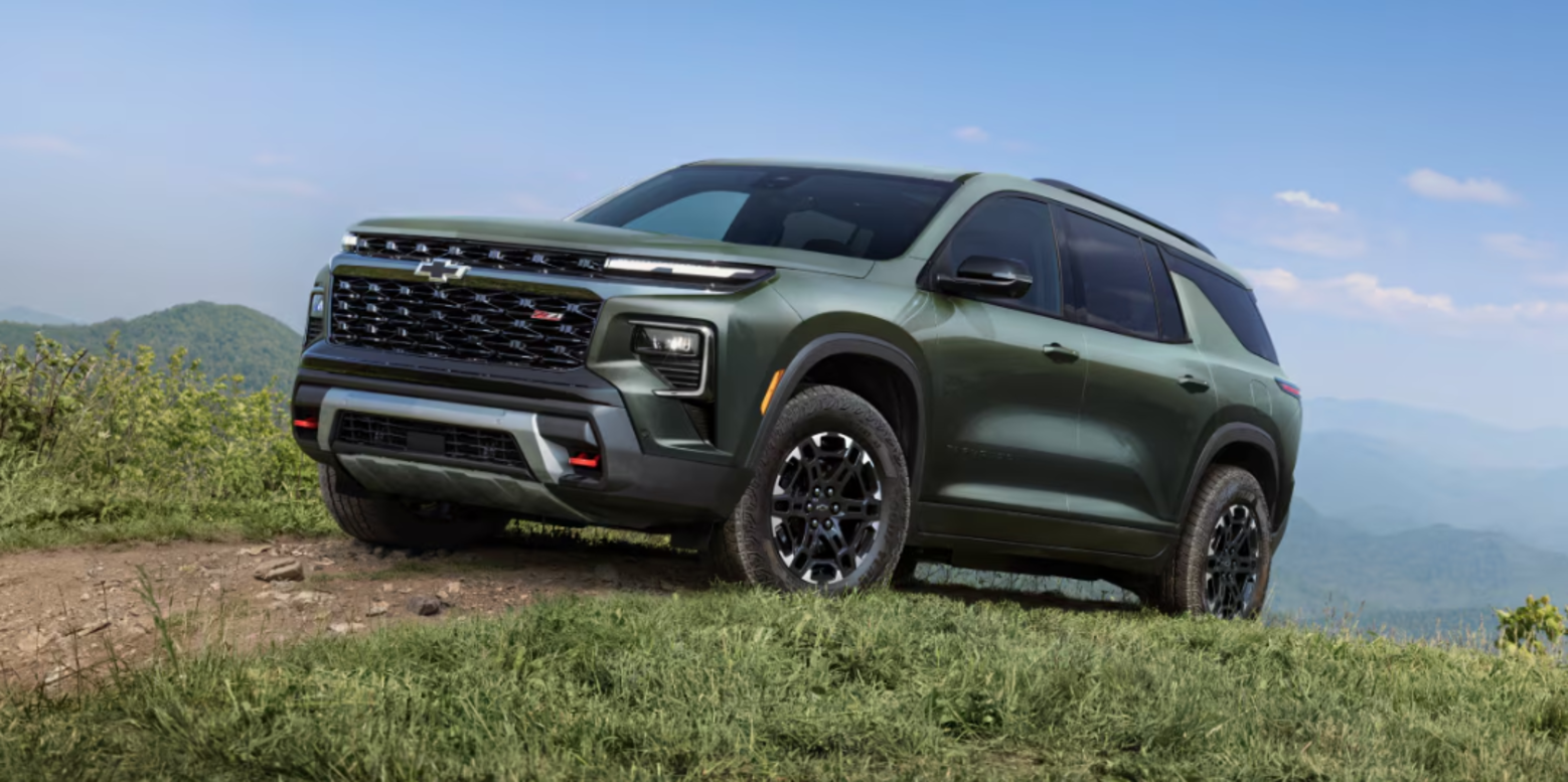 A green Chevrolet Traverse cresting the top of a hill while driving off-road.