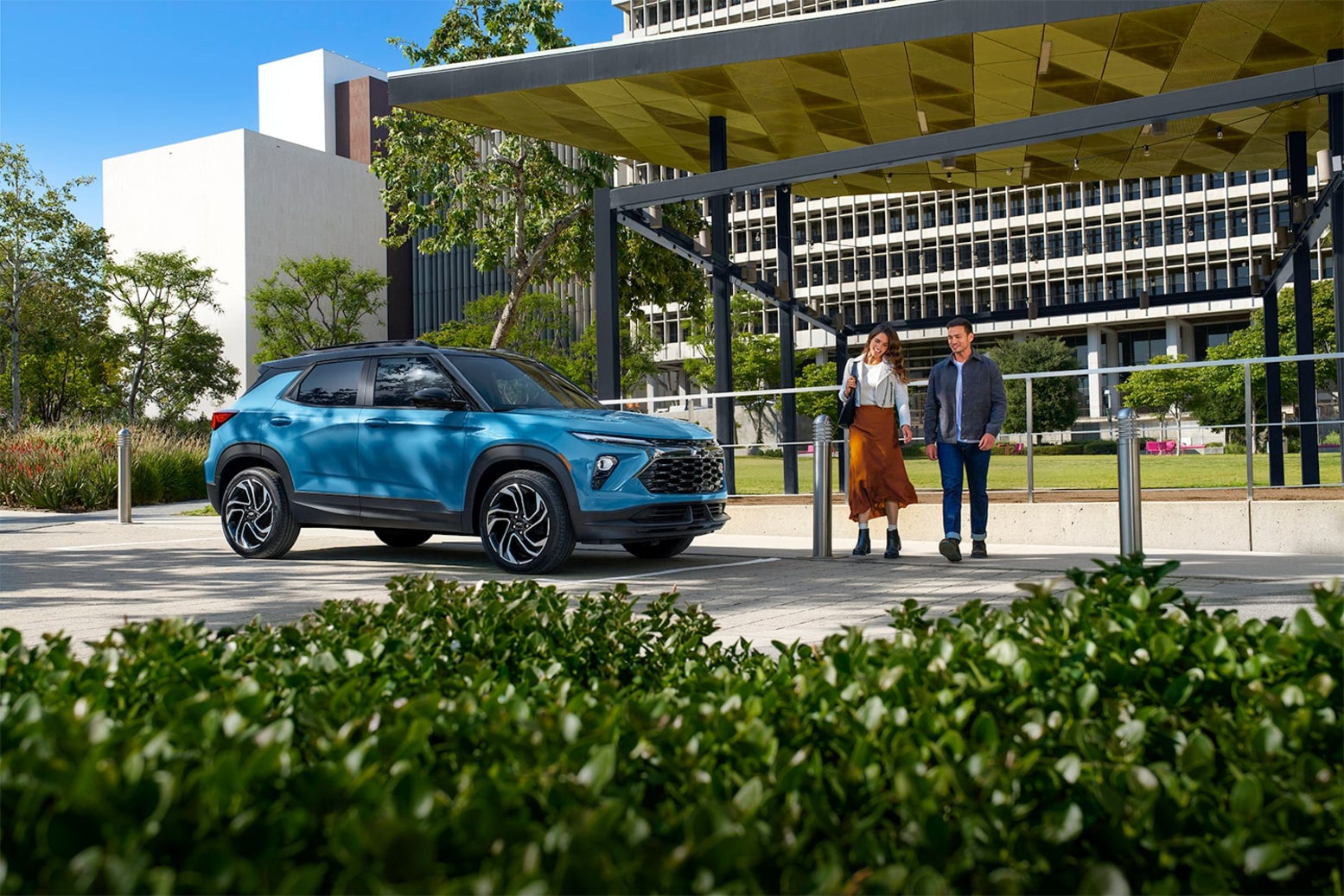 A blue Chevy Trailblazer parked with a couple walking to it.